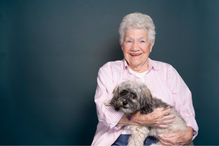 Woman holding her dog at home, representing comfort and independence while receiving support to live safely at home.