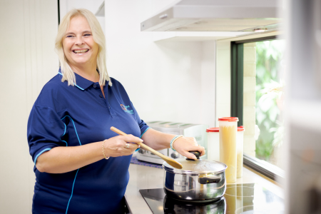Home care worker preparing a meal in a client’s kitchen, supporting safe and independent living at home.